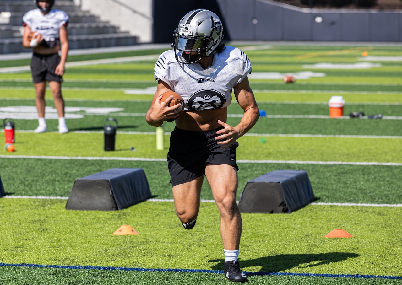 Athlete in equipment running with the ball in a drill